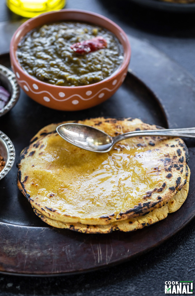 a spoon of ghee placed on a stack of makki ki roti