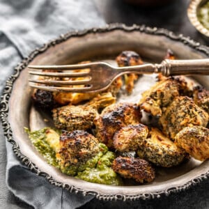 a roasted broccoli floret dipped in cilantro chutney with more roasted broccoli in the plate