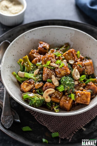 tofu broccoli stir-fry served in a white bowl with a spoon placed on the side