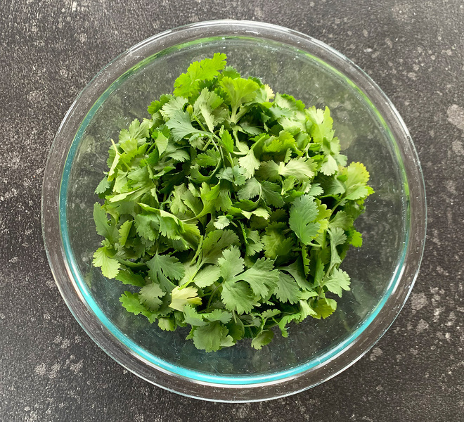 glass bowl filled with fresh cilantro leaves