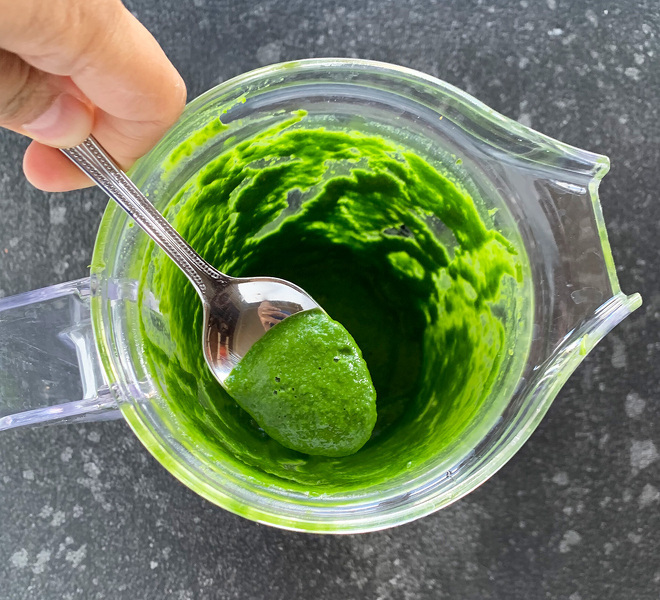 a spoon scooping out cilantro chutney from a blender