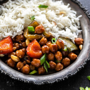 picture of kung pao chickpeas served along with white rice in a rimmed silver plate