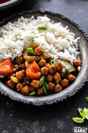 picture of kung pao chickpeas served along with white rice in a rimmed silver plate