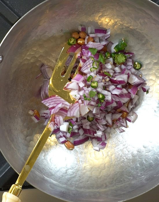 onions and curry leaves being added to kadai
