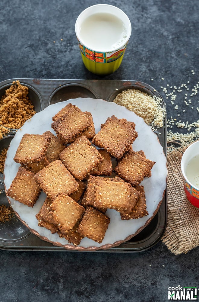 baked gur para arrange on a white round marble with a glass of milk on the side and one on the back