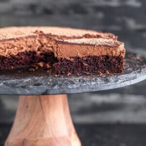 slice of eggless chocolate mousse cake placed on a black cake stand with another slice placed in a plate