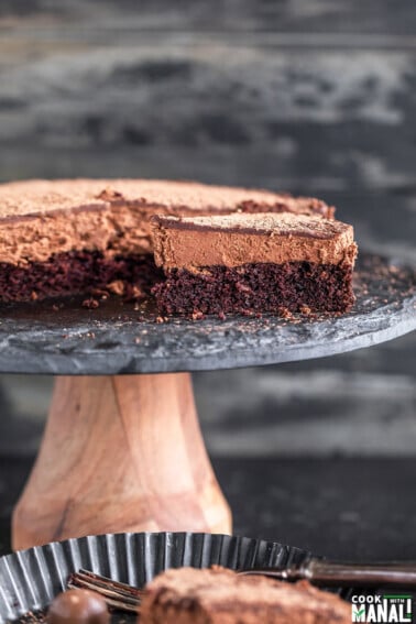 slice of eggless chocolate mousse cake placed on a black cake stand with another slice placed in a plate