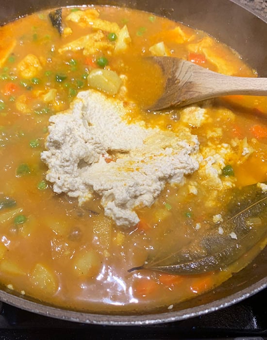 coconut paste being added to a curry