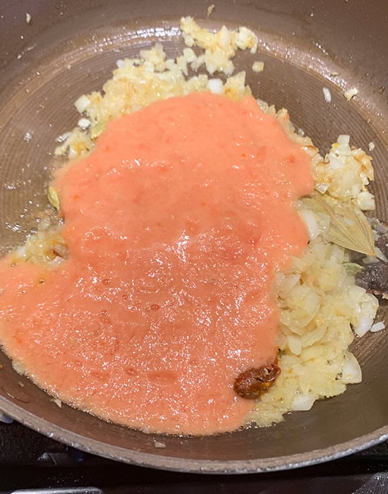 onions with tomato puree and spices in a pan