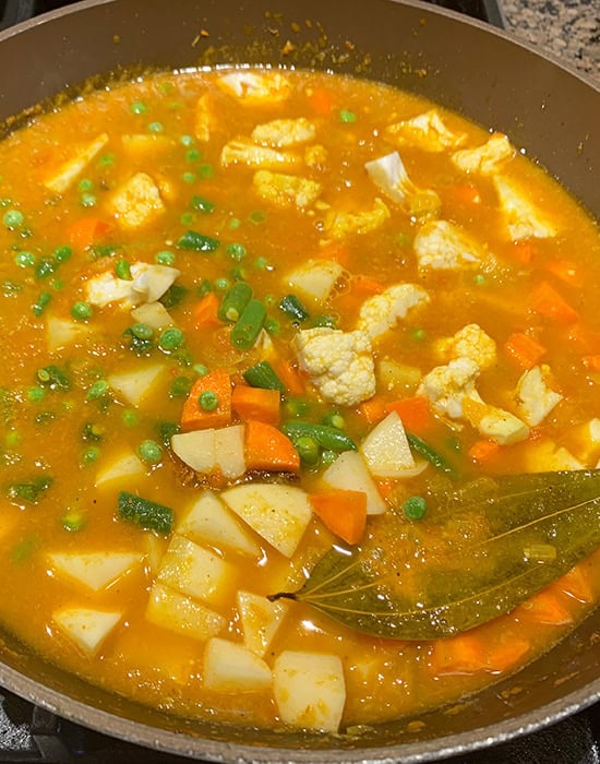 water added to a vegetable curry in a pan