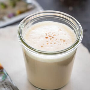 london fog tea latte served in a glass jar with sachet of tea bag lying in the background and one on the side