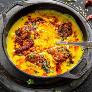 punjabi kadhi pakora served in a cast iron kadai with cilantro and broken red chilies scattered in the background