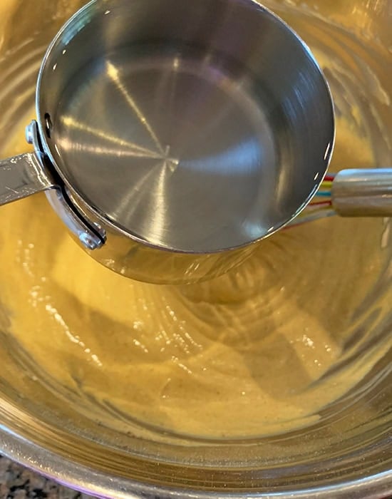 adding water to kadhi in a steel bowl