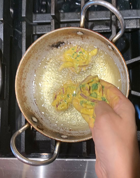 hand adding pakoras to hot oil