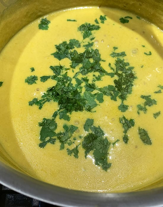 chopped cilantro added to pot of kadhi