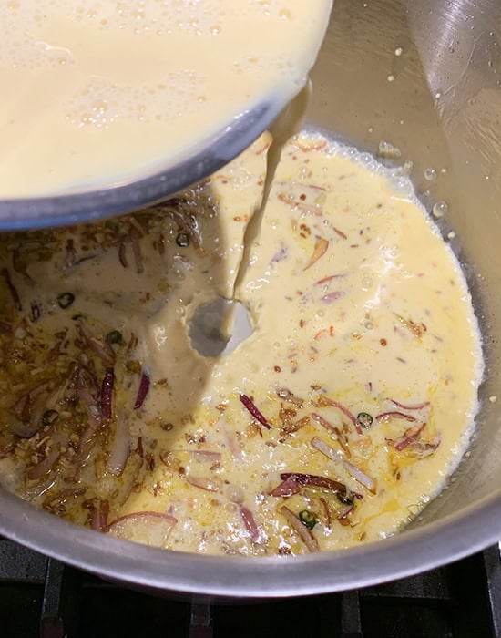 adding kadhi batter to the steel pot