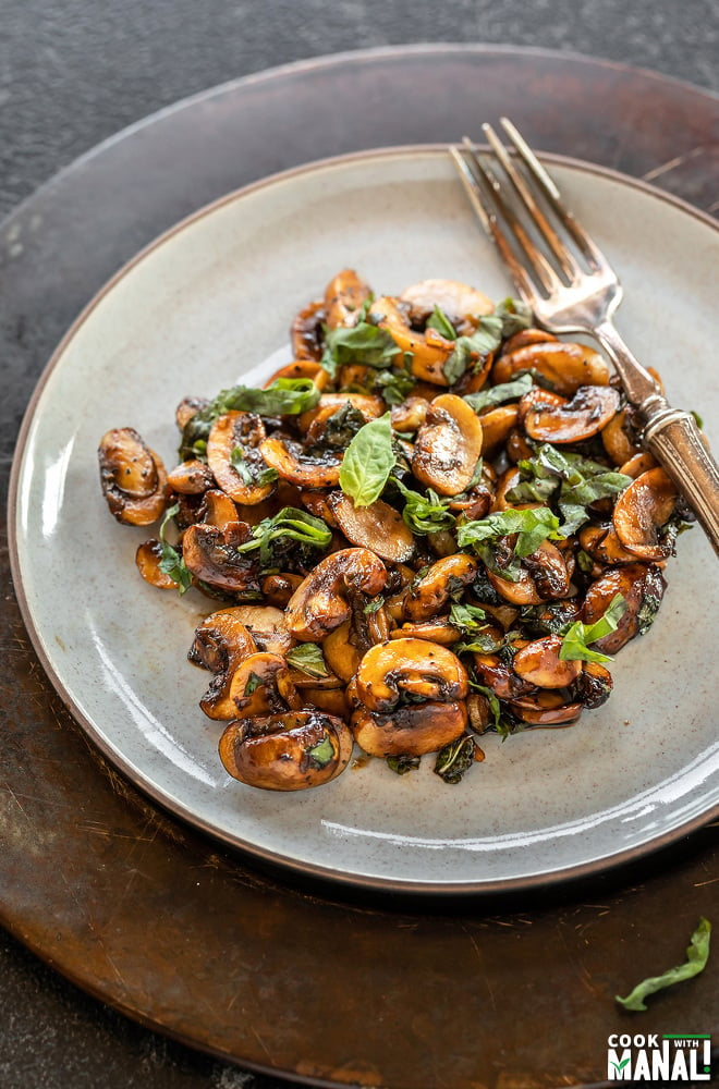 mushrooms garnished with basil and served in a plate with fork