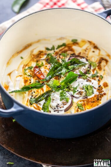 eggplant and yogurt dish garnished with curry leaves, cilantro and spices served in a round dutch oven