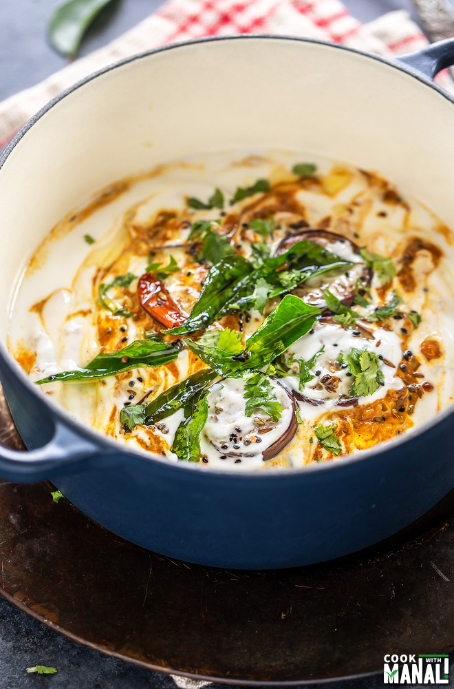 eggplant and yogurt dish garnished with curry leaves, cilantro and spices served in a round dutch oven
