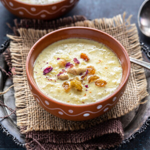 lauki kheer served in a clay bowl garnished with nuts, raisins and dried rose petals