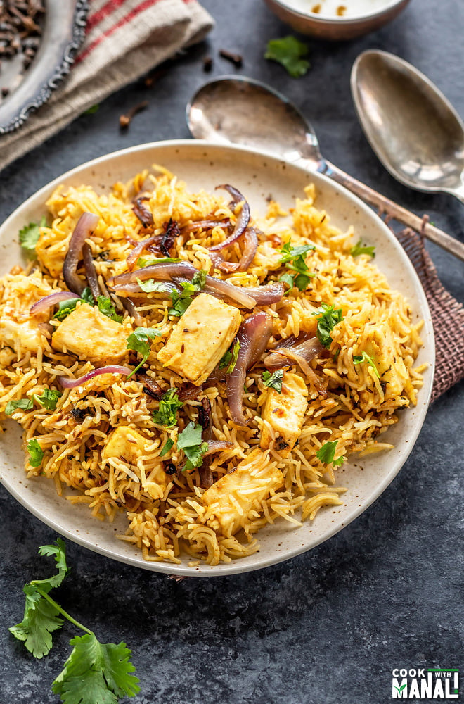 plate full of rice and paneer, garnished with cilantro and browned onions