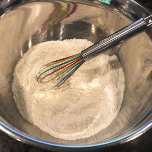 photo of flour in a steel bowl with a whisk