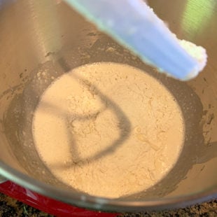 flour and milk being added to a batter in a stand mixer