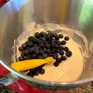blueberries being added to a batter in a stand mixer