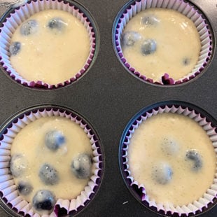 muffin liners filled with muffin batter with blueberries