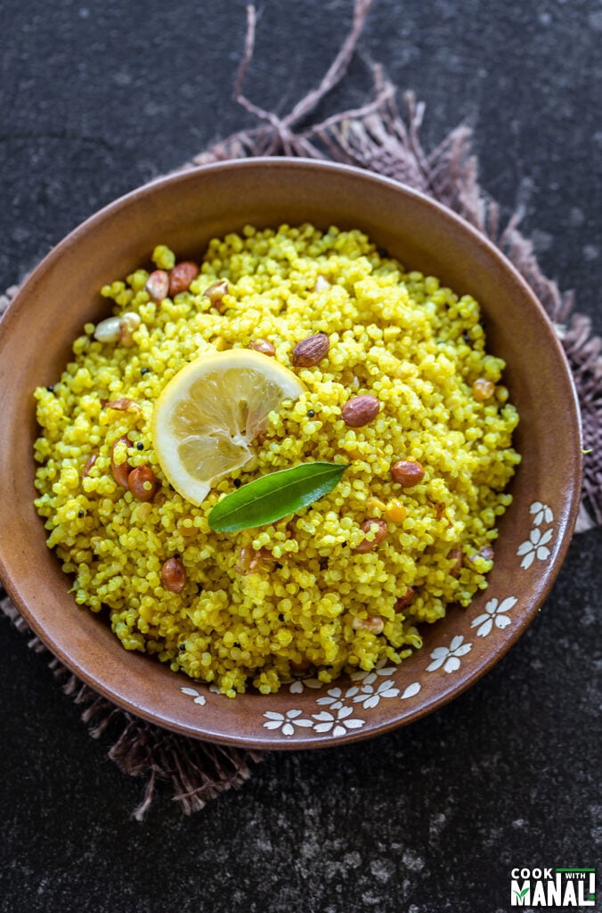 bowl of quinoa garnished with lemon wedge, curry leaves