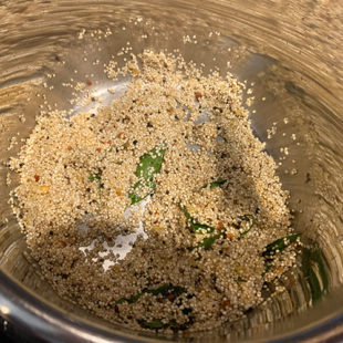steel pot with uncooked quinoa, curry leaves