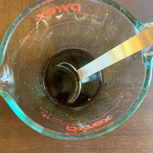 a soy sauce based sauce in a measuring jar with a measuring spoon