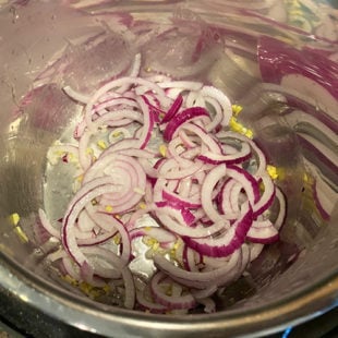 instant pot with sliced onions being sauteed in it