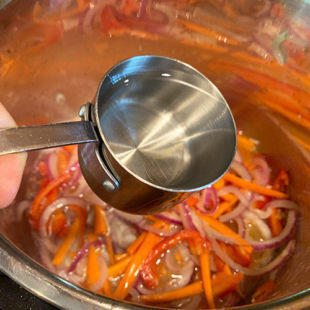 water being added to an instant pot with carrots and onions