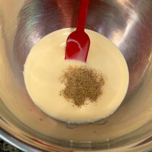 bowl with condensed milk and ground cardamom with a red spatula