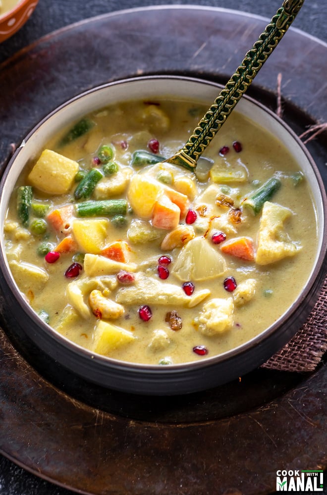 yellow color vegetable curry served in a bowl with a golden color spoon