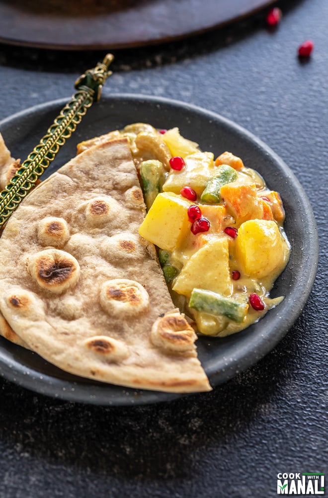 a small plate with a tandoori roti placed on one side and a curry placed on the other side