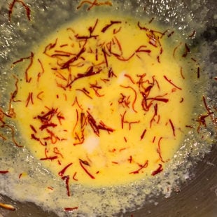 milk with saffron strands giving the mixture a yellow color