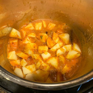 cubes of potato in a red color gravy in the instant pot