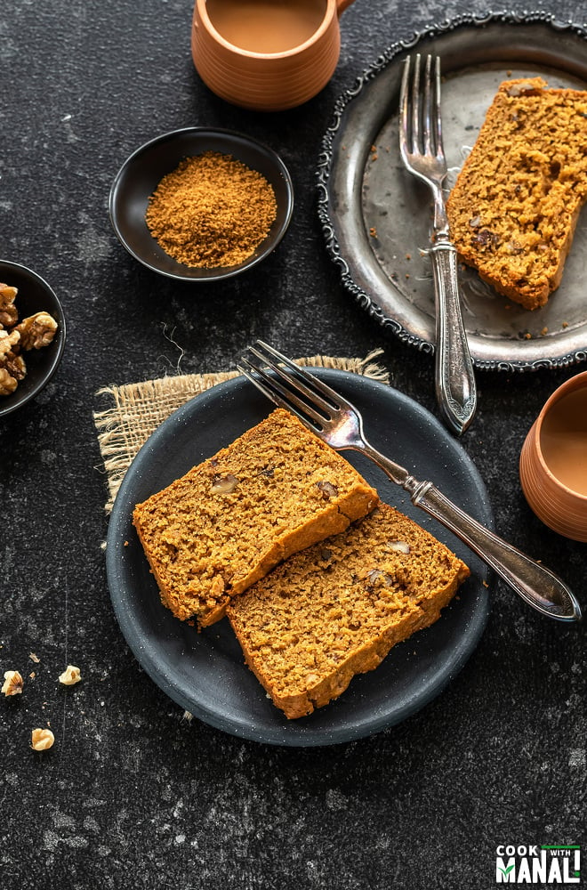 overhead shots of whole wheat jaggery cake slices placed in two plates and cups of chai on the side