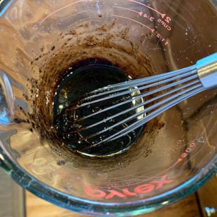 a thick dressing being whisked with a hand whisk in a glass measuring jar