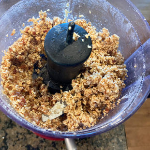 food processor with a mixture of oats, sesame seeds and dates
