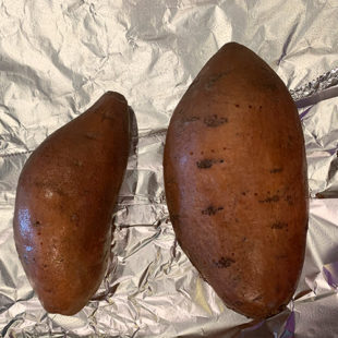 two sweet potatoes placed on an aluminium foil