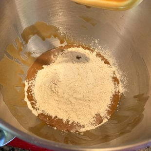 flour being added to a batter in the steel bowl of a stand mixer