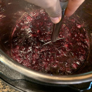 blueberries being mashed with a potato masher