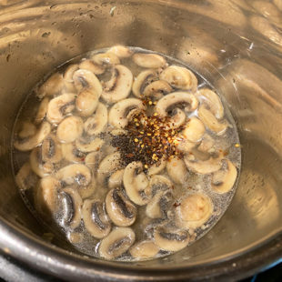 mushrooms with water, pepper and chili flakes in a steel pot