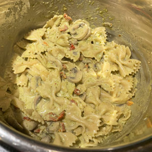 bow-tie pasta mixed with a creamy sauce in a steel pot