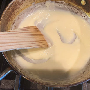 spatula stirring milk powder and cream in a pan