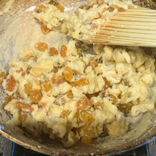 cashews, raisins with cream and milk powder mixture in a pan