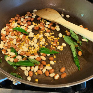 peanuts with chana dal, curry leaves being roasted in a pan